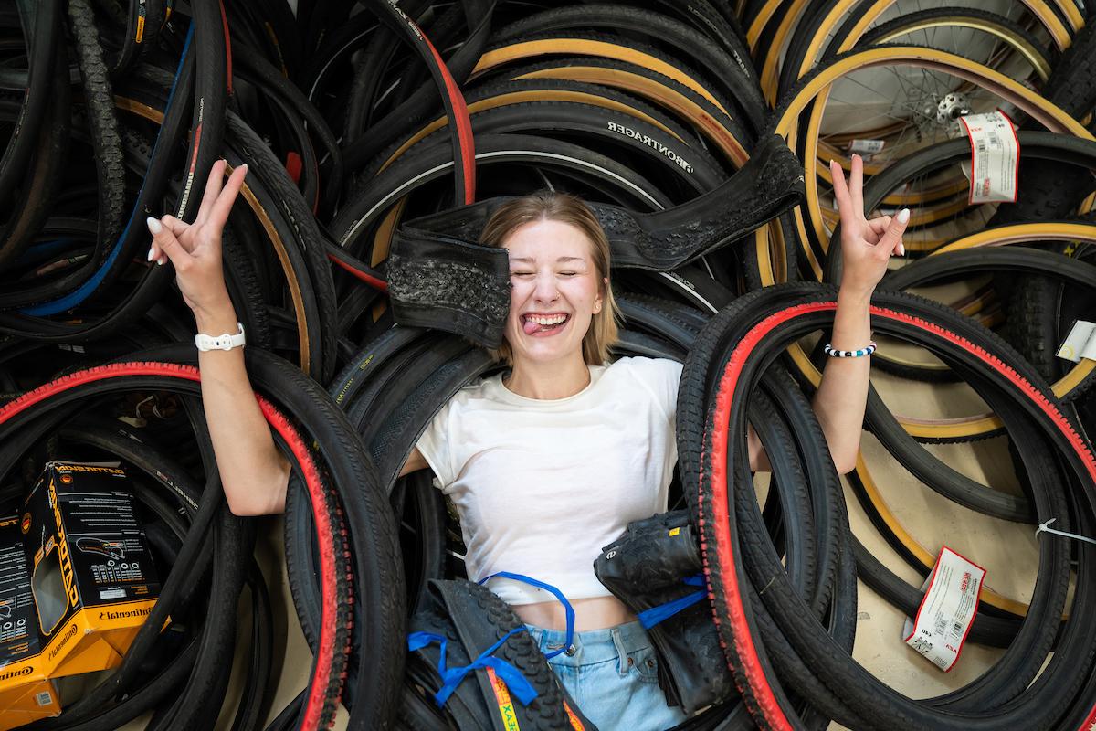 阿拉贝拉·卡明斯在一堆自行车轮胎上举着和平标志.